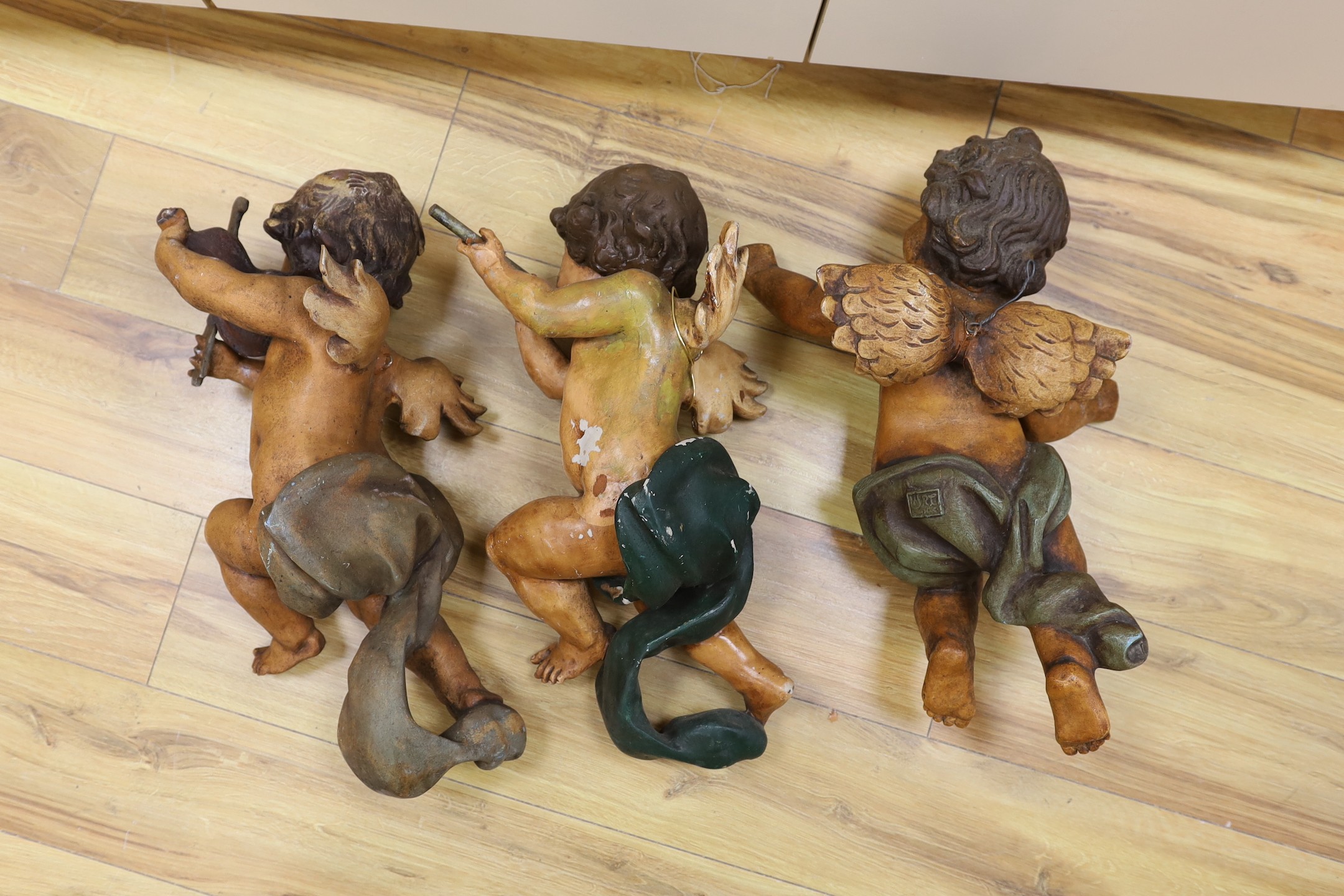 A trio of plaster cherubs with instruments